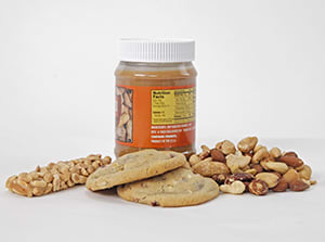 Una barrita de muesli, un tarro de mantequilla de cacahuate, galletas y frutos secos variados.
